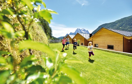 Stabingerhof: Urlaub auf dem Bauernhof für die ganze Familie Eine Familie beim Spielen und Toben auf der großen Wiese hinter den Chalets