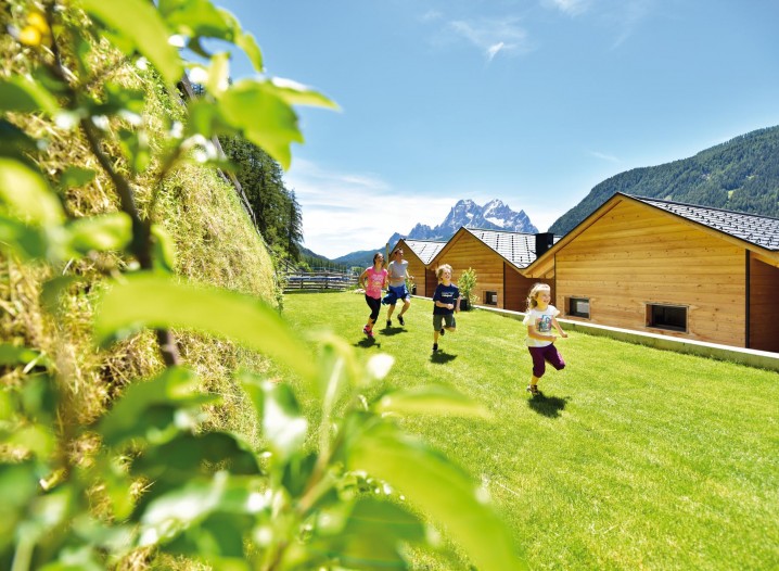 Eine Familie beim Spielen und Toben auf der großen Wiese hinter den Chalets
