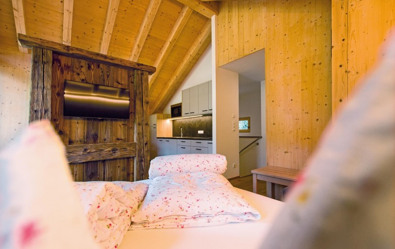 Stabingerhof: Chalets mit Wohnküche und Zimmern Das Bett mit Blick auf die Küche im Chalet Anton