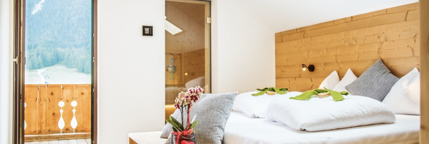 Ein gemütlich eingerichtetes Chaletzimmer in Sexten mit Balkon