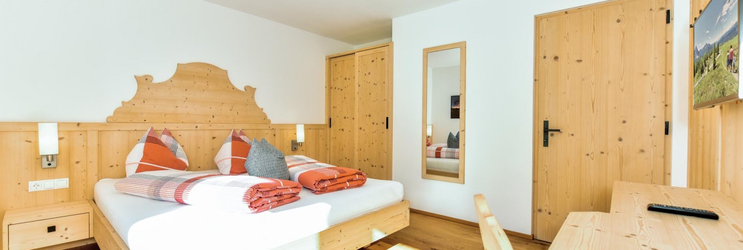 Das Zimmer von Chalet Susi mit Doppelbett, Schreibtisch, Fernseher, Schrank und Spiegel
