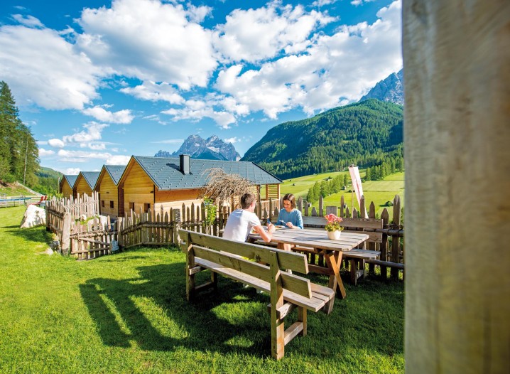 Ein Pärchen auf einer Bank auf der Wiese vor den Chalets vom Stabingerhof